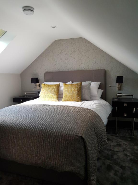 a bedroom with a large bed with yellow pillows at The Queens Head, Parkside Apartment 4 in Burley in Wharfedale
