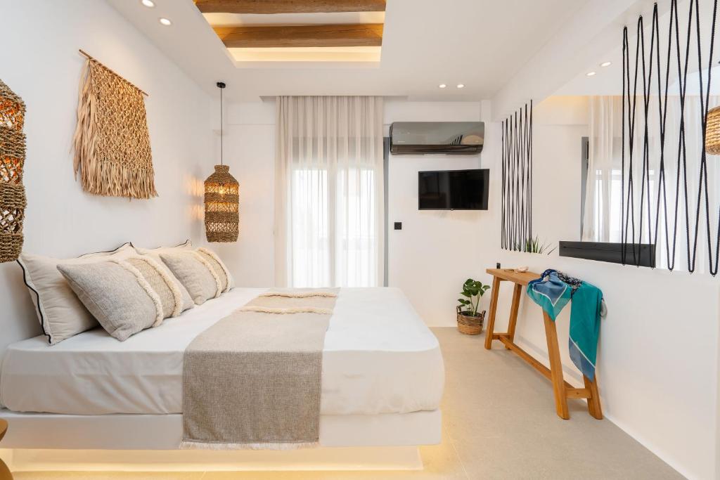 1 dormitorio blanco con 1 cama y TV en ElVirtus Suites, en Naxos Chora
