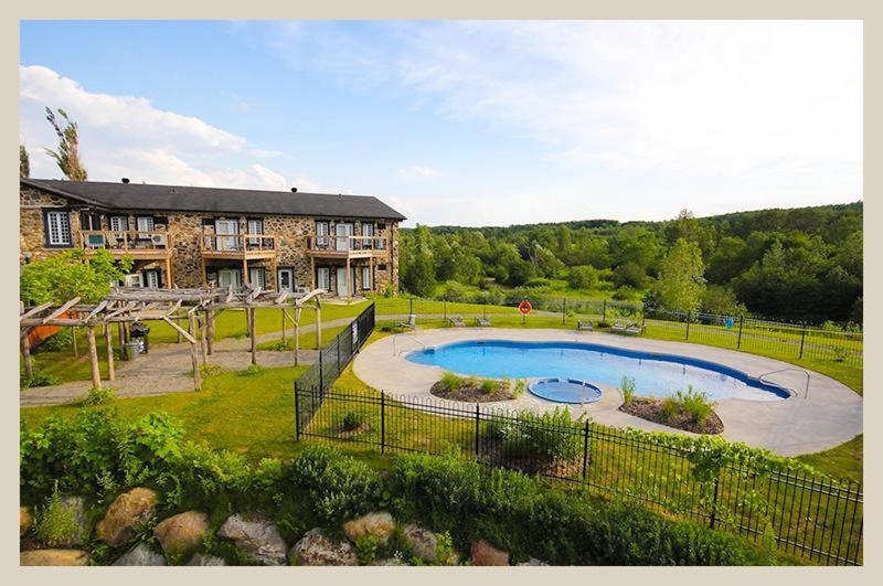 una casa grande con un patio con piscina en Condos Vacances Orford Suite 1 chambre en Orford