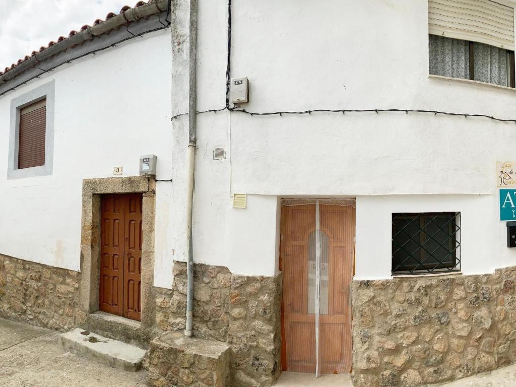 a white building with brown doors and a stone wall at Holiday Home in Villamiel with Mountain Views in Villamiel