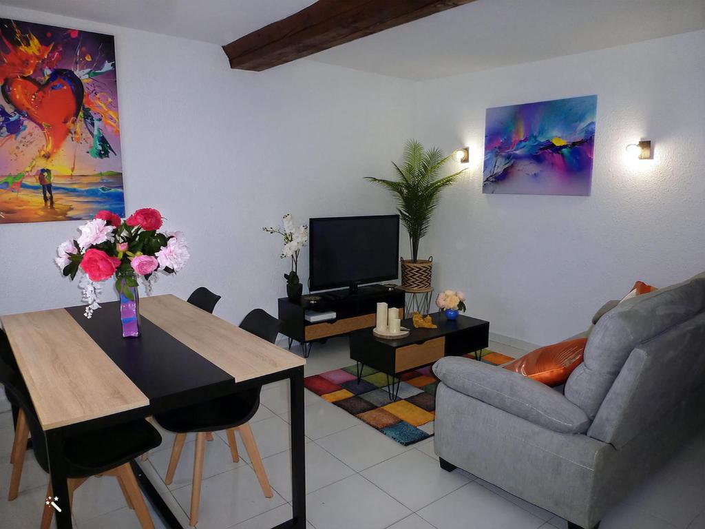 sala de estar con sofá y mesa con flores en Le Scoubidou, en Perpiñán