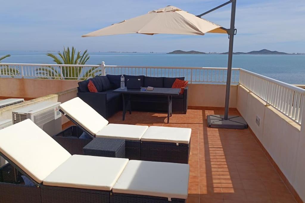 un patio con sofá y sombrilla en Beachhouse, Beautiful space, beautiful sea view, on the beach, en Cartagena