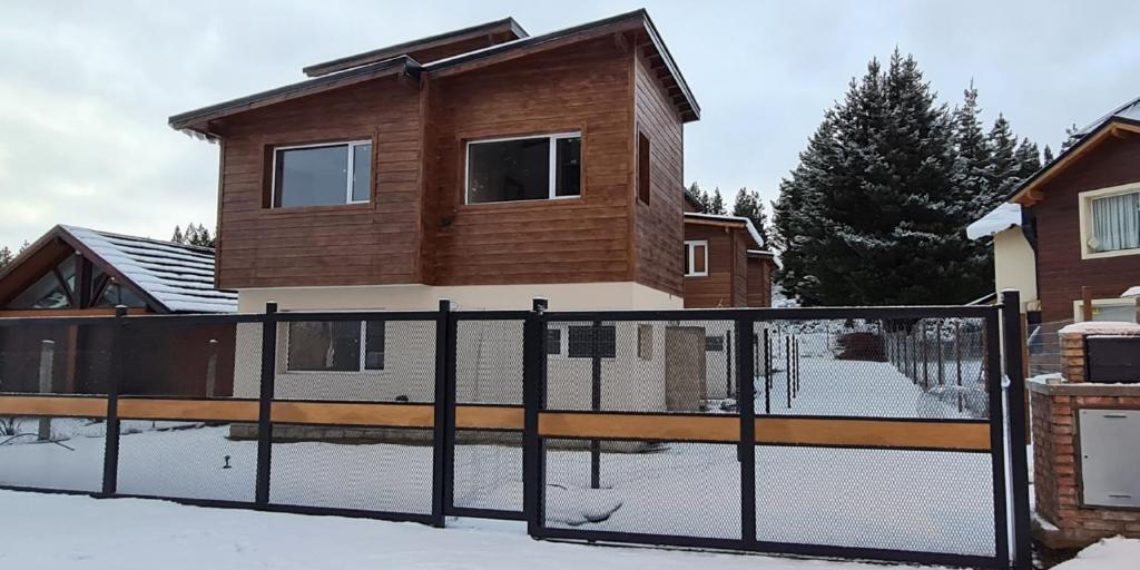 una cerca frente a una casa en la nieve en PH Design Entre Pinos en San Carlos de Bariloche