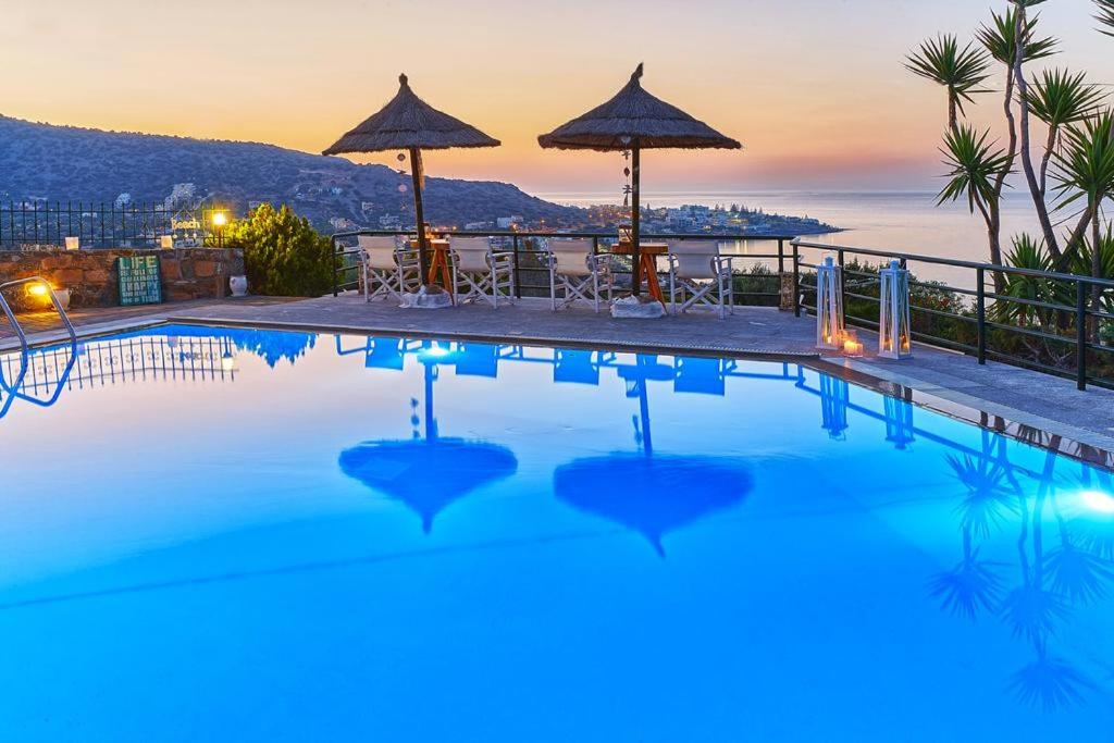 a pool with a view of the ocean at dusk at Everest Apartments and Suites in Stalida
