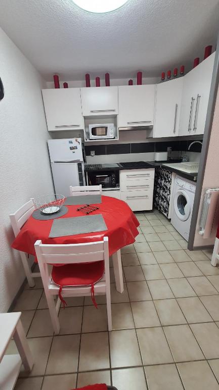 - une cuisine avec une table et une nappe rouge dans l'établissement JOLI T2 DANS UN ECRIN DE VERDURE n 2, à Digne-Les-Bains