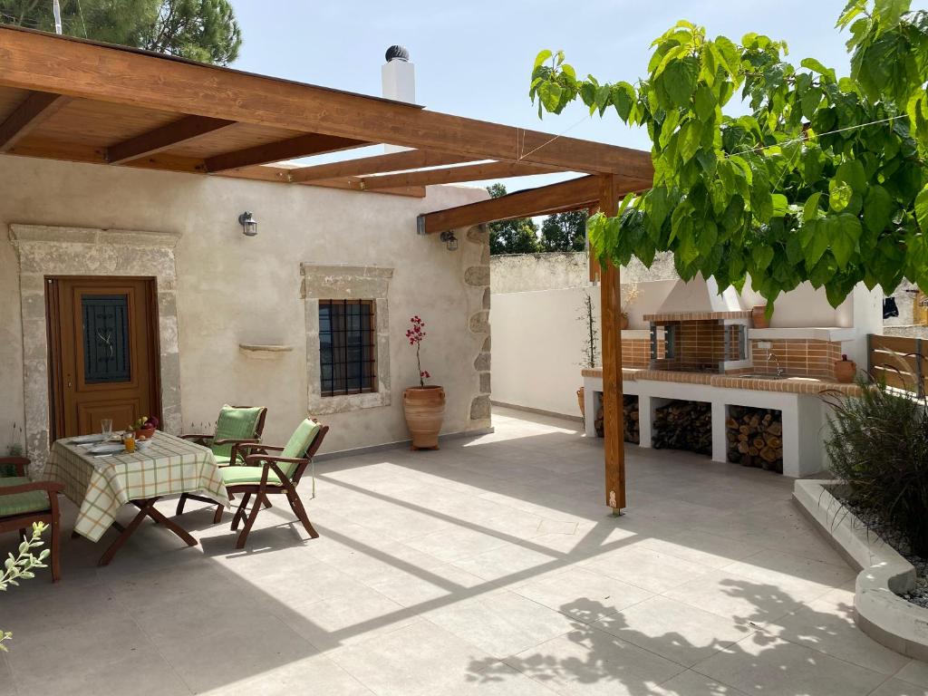 een patio met een tafel en stoelen en een pergola bij Avli House Vori in Vóroi