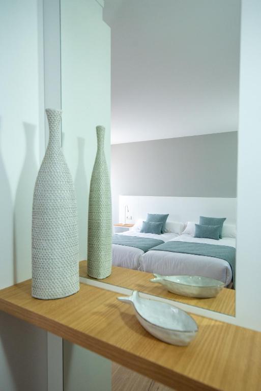 two vases sitting on a wooden table with a bed at LAR DA REVOLTA in Cedeira