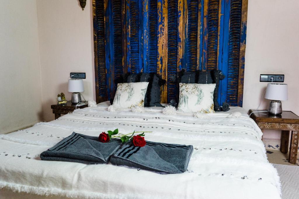 Una cama blanca con dos rosas rojas. en Riad Bianca Marrakech en Marrakech