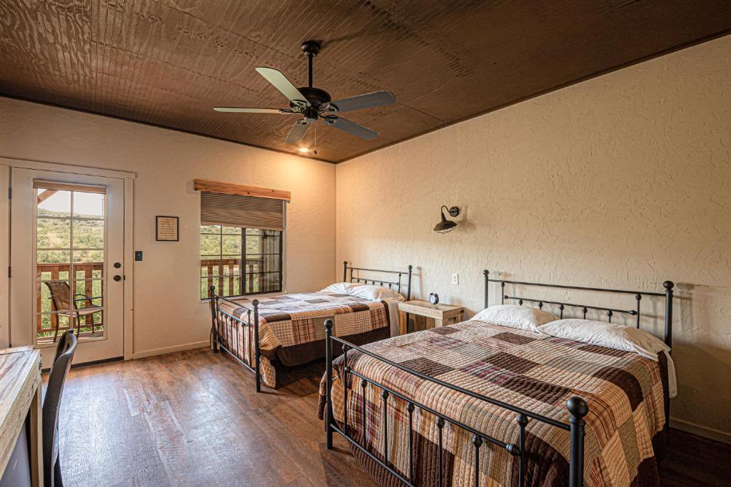 a bedroom with two beds and a ceiling fan at Miners Cabin #3 -Two Double Beds - Private Balcony - Walk to the Action in Tombstone