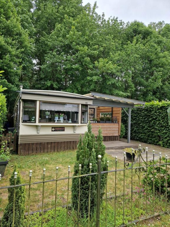 een klein huis in een tuin met een hek bij Ruime chalet nabij Giethoorn in De Pol