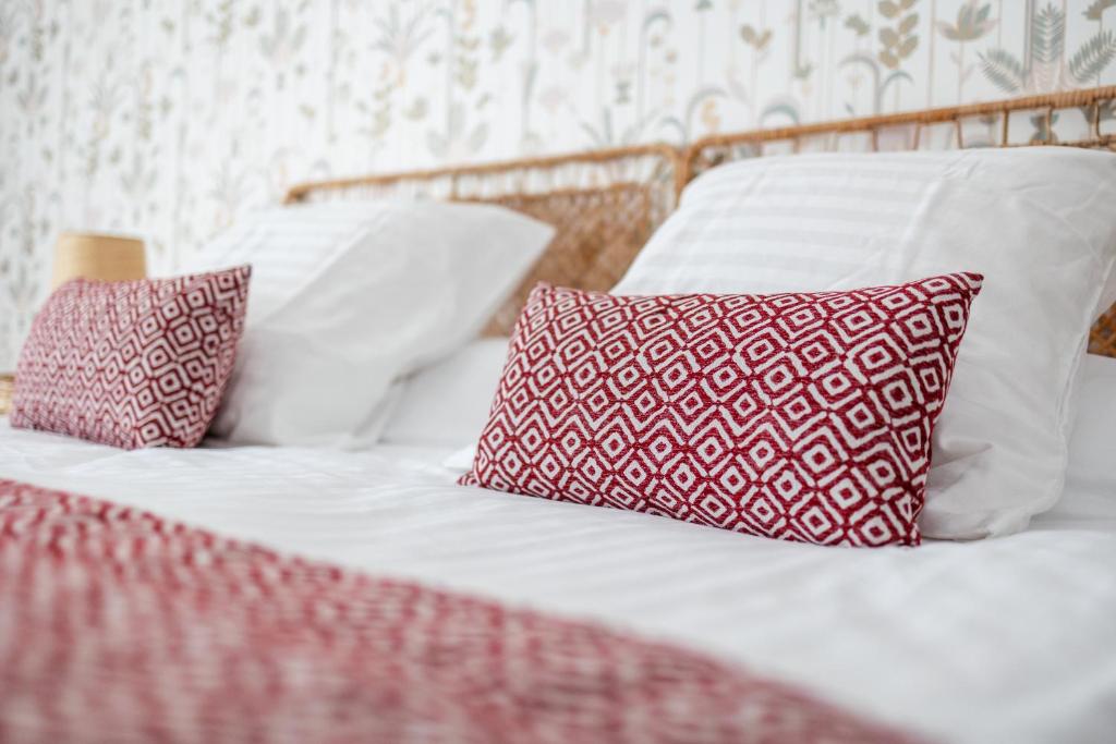 two beds with red and white pillows on them at Maison Alfred et Agatha in Pleudihen-sur-Rance