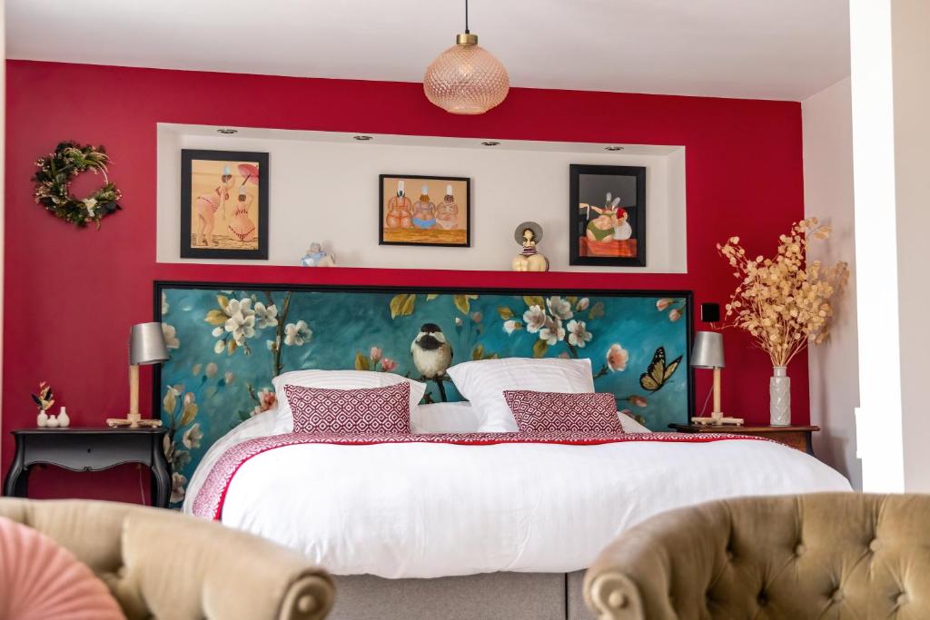 a bedroom with a large bed with red walls at Maison Alfred et Agatha in Pleudihen-sur-Rance