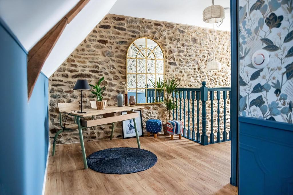 a room with a desk and a stone wall at Maison Alfred et Agatha in Pleudihen-sur-Rance