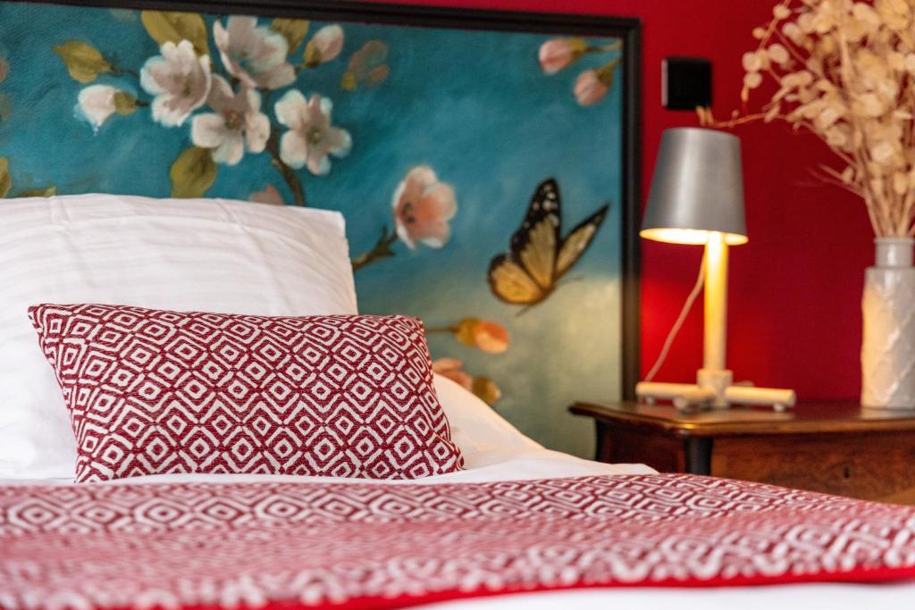 a bedroom with a bed with a pillow and a butterfly painting at Maison Alfred et Agatha in Pleudihen-sur-Rance