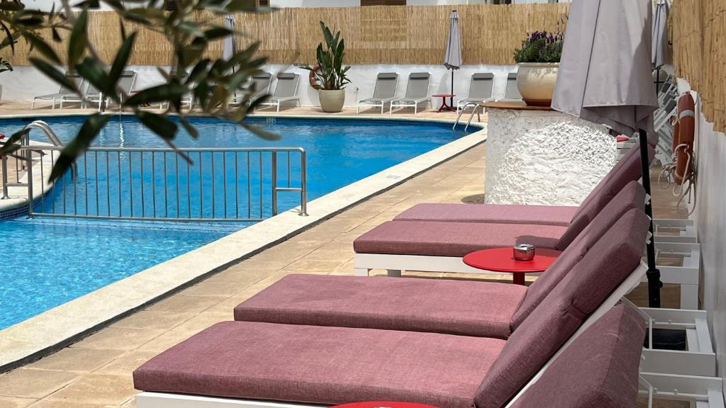 - une piscine avec 2 chaises longues et une table dans l'établissement Aparthotel Boutique Poniente Playa, à Sant Antoni de Portmany