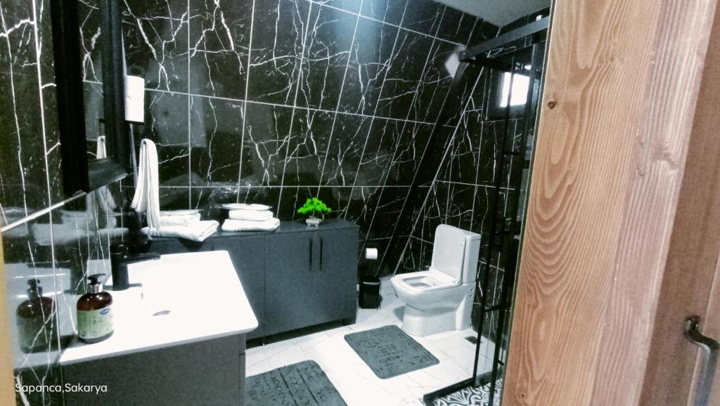 a black tiled bathroom with a sink and a toilet at Sapanca Dağaltı Bungalov in Sapanca