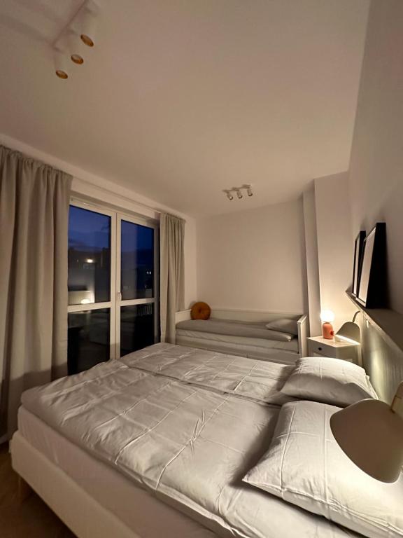 1 cama blanca grande en un dormitorio con ventana en Apartament na Letniej z dużym tarasem z widokiem na góry en Kłodzko