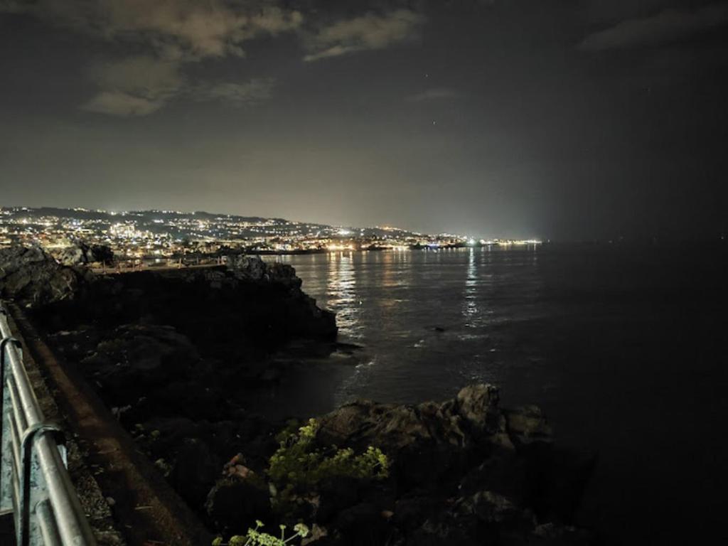 a view of the ocean at night with a city at Venere B&B in Catania