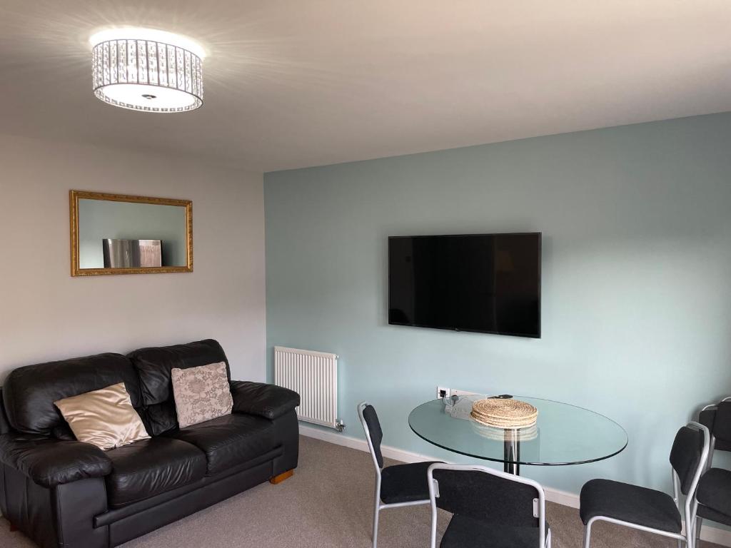 uma sala de estar com um sofá de couro preto e uma mesa de vidro em 3 bed house with parking near airport em Edimburgo