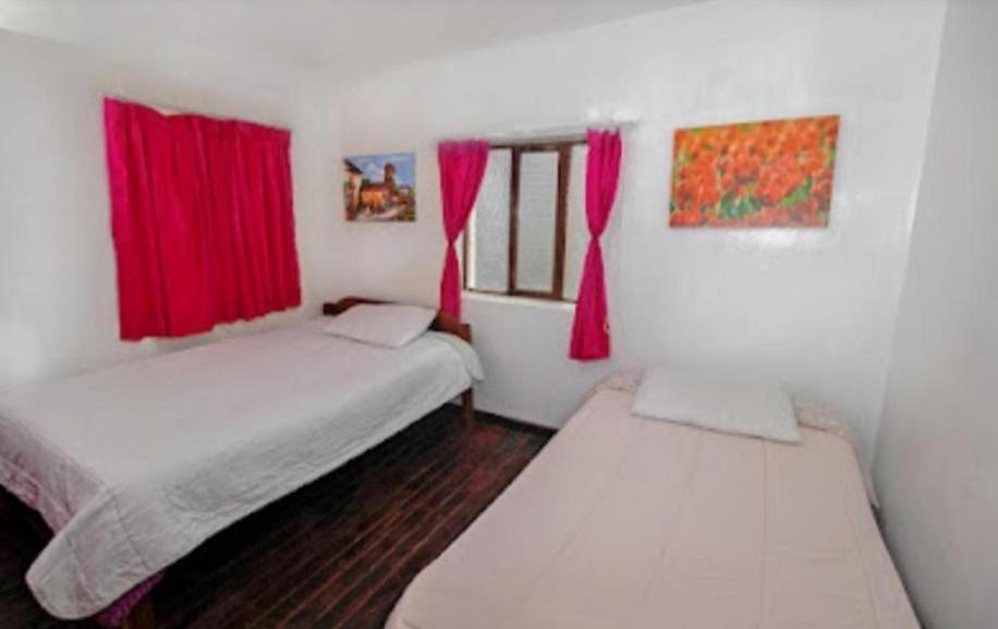 two beds in a room with red curtains at Pink Sheep Hostal in Cusco
