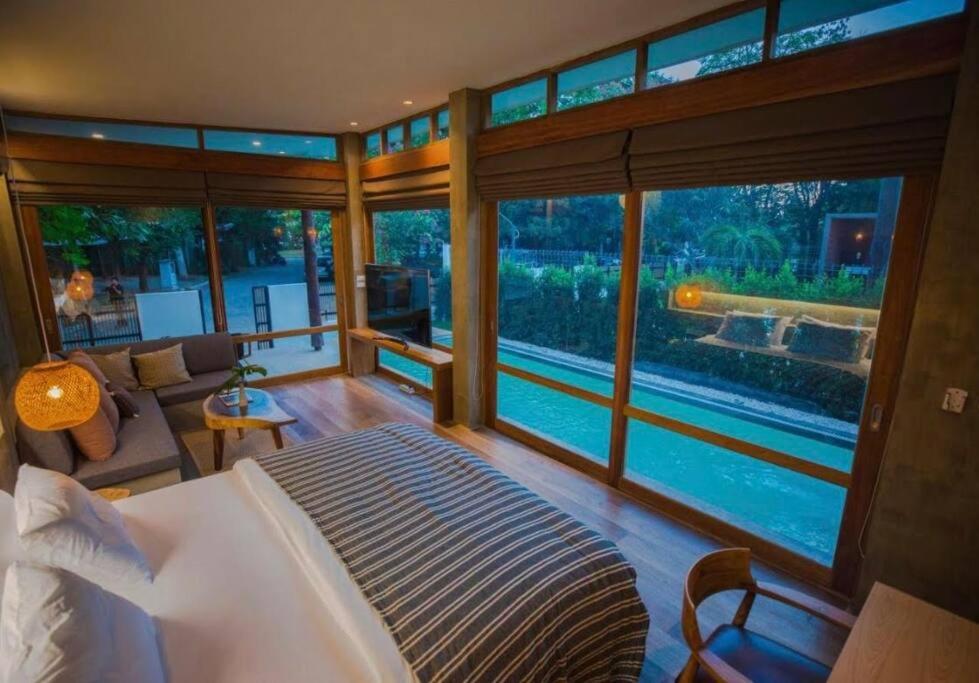 1 dormitorio con cama grande y ventana grande en Chiangmai Boutique Pool Villa, en Chiang Mai