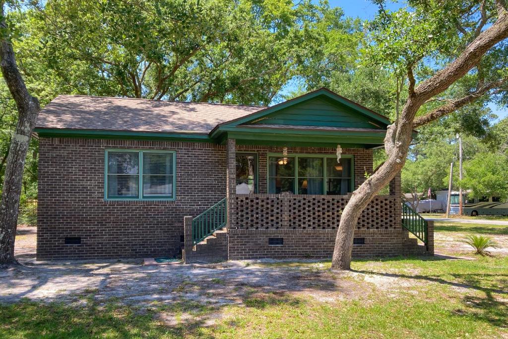 una pequeña casa de ladrillo con un árbol delante de ella en The Little Brick Cottage en Myrtle Beach