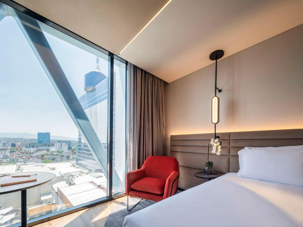um quarto de hotel com uma cama e uma cadeira vermelha em Novotel Mexico City World Trade Center em Cidade do México