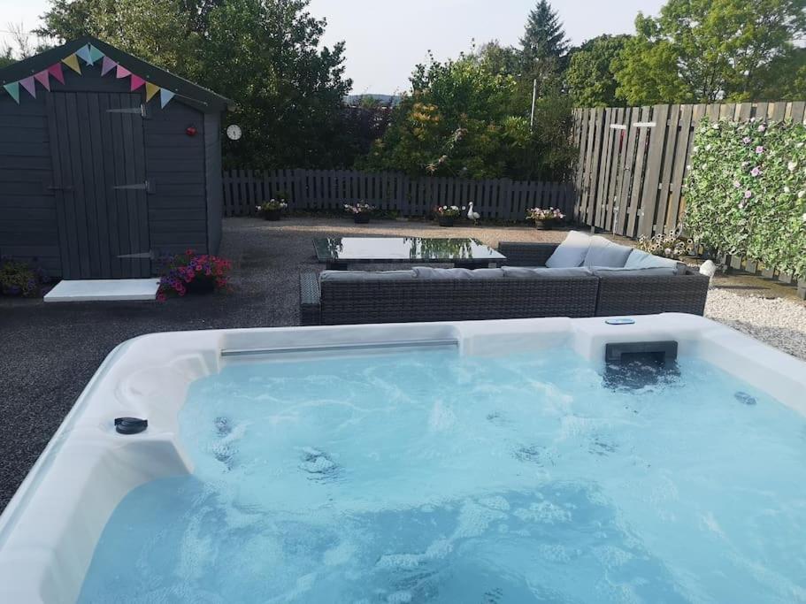 a large hot tub in a yard with a couch at Strathken Cottage in Castle Douglas