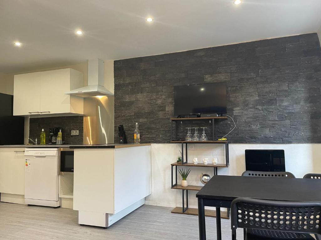 une cuisine avec des placards blancs et une table noire dans l'établissement Maison duplex vue cité, à Carcassonne
