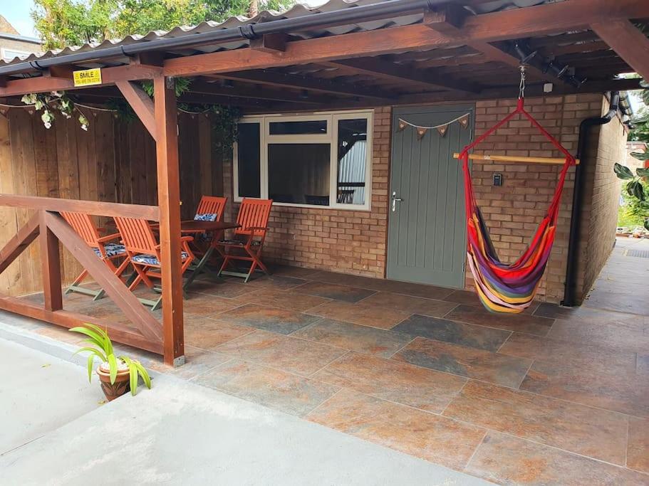 a patio with a hammock hanging from a house at DOG FRIENDLY little bungalow with patio & private driveway in Kessingland
