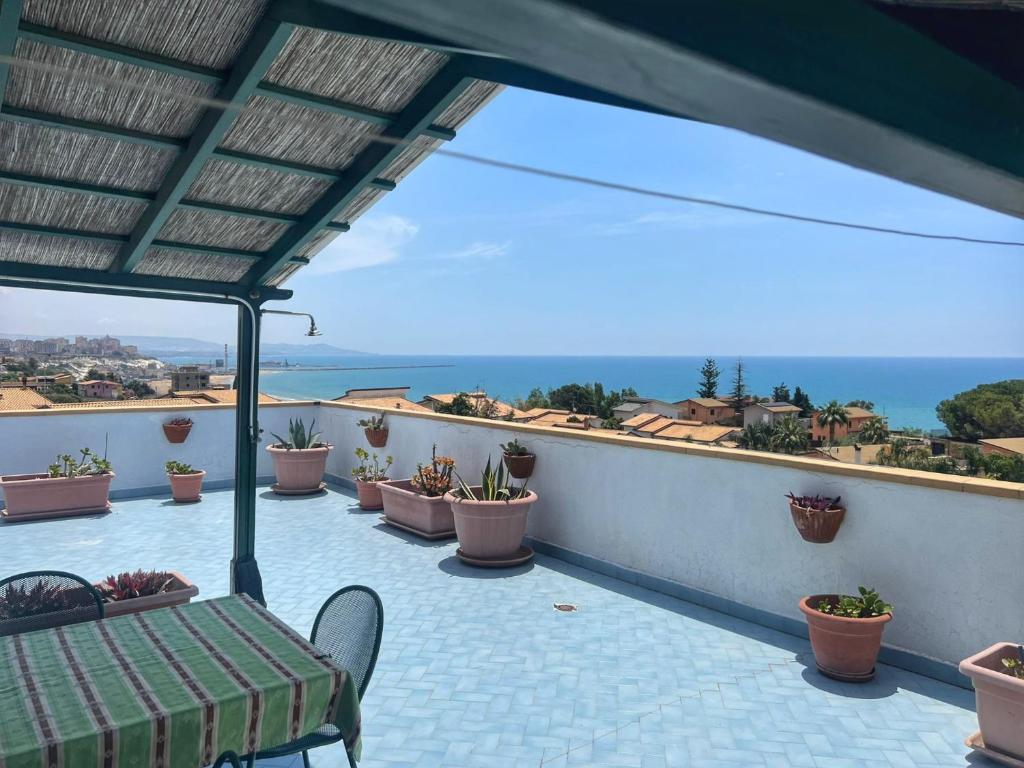 un balcón con una mesa, macetas y el océano en LA TERRAZZA SUL MARE, en Porto Empedocle