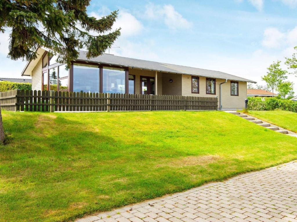 uma casa com um relvado verde em frente em 5 person holiday home in Juelsminde em Sønderby