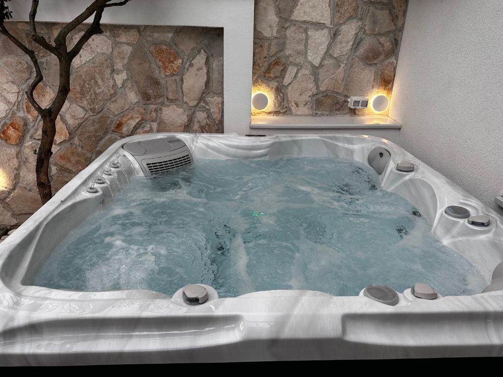 a jacuzzi tub in a bathroom with a stone wall at Sweet House MARCELLA in Imotski