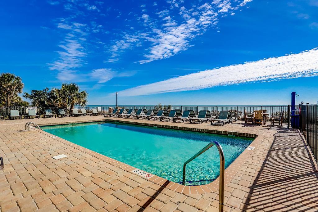 a swimming pool with chairs and the ocean in the background at Bluewater Resort 816 in Myrtle Beach