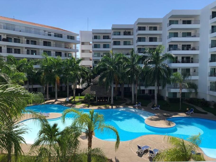 una gran piscina con palmeras frente a un edificio en Condominio c/ alberca y vista a Marina Mazatlán en Mazatlán