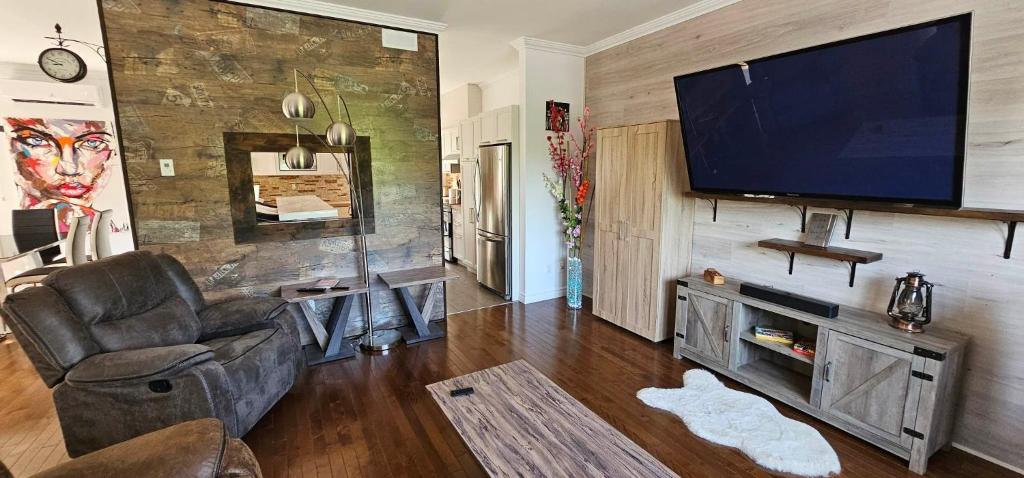a living room with a flat screen tv on a wall at Superbe propriété moderne en nature in Sainte Brigitte de Laval