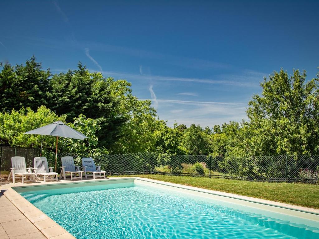 a swimming pool with two chairs and an umbrella at Maison Girou Haut in Montcabrier