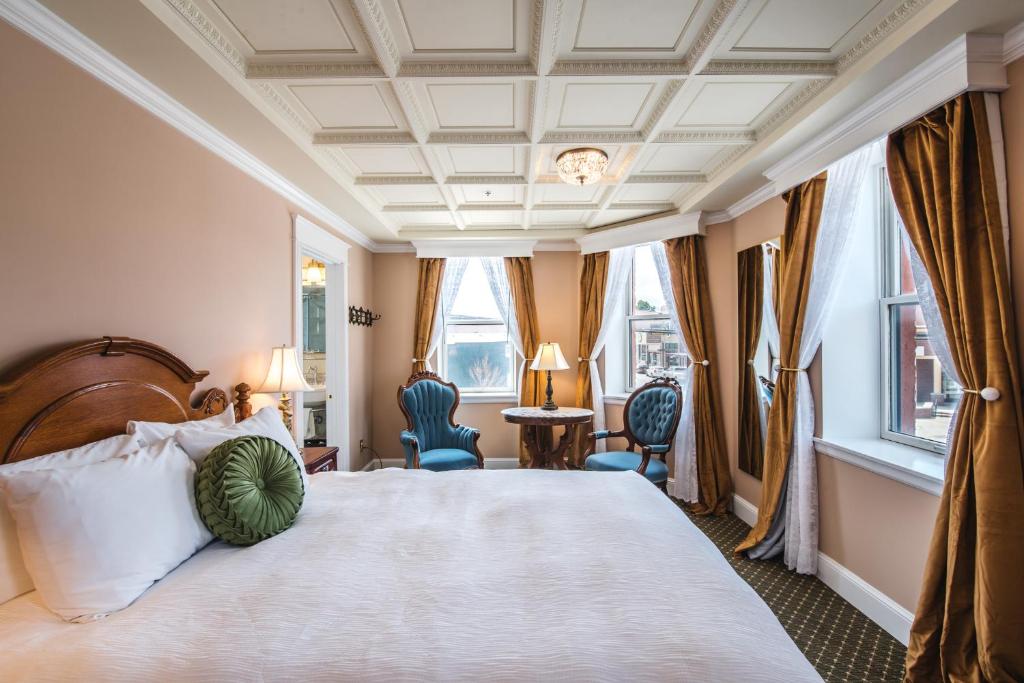una camera da letto con un grande letto con due sedie e finestre di The Pollard Hotel a Red Lodge