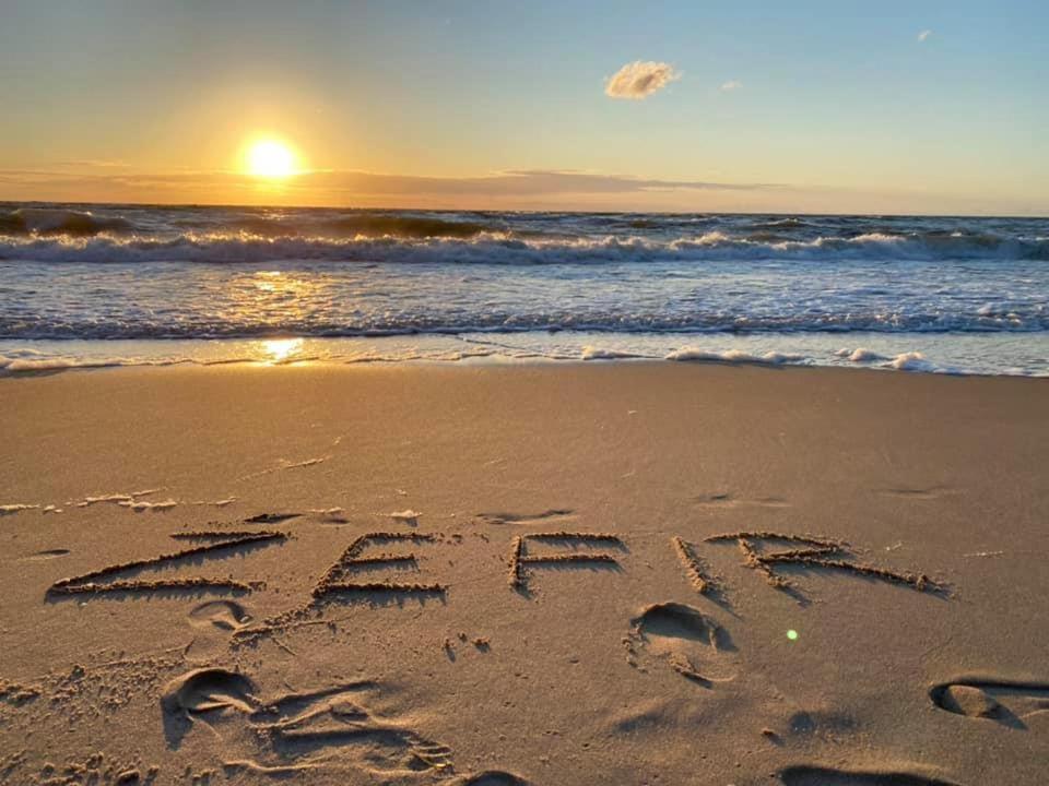 a word written in the sand on a beach at Zefir Domek nr 5 in Dąbki