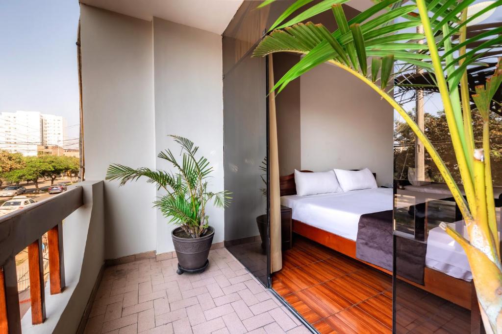 a bedroom with a bed on a balcony with plants at Hotel Portada Del Sol in Trujillo
