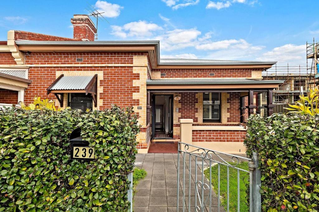 ein Backsteinhaus mit einem Tor davor in der Unterkunft Azami - Charming Gilbert Cottage in Adelaide