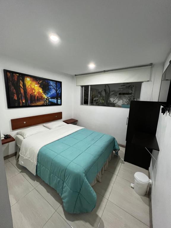 a bedroom with a bed and two pictures on the wall at Hotel Tempus in Pasto