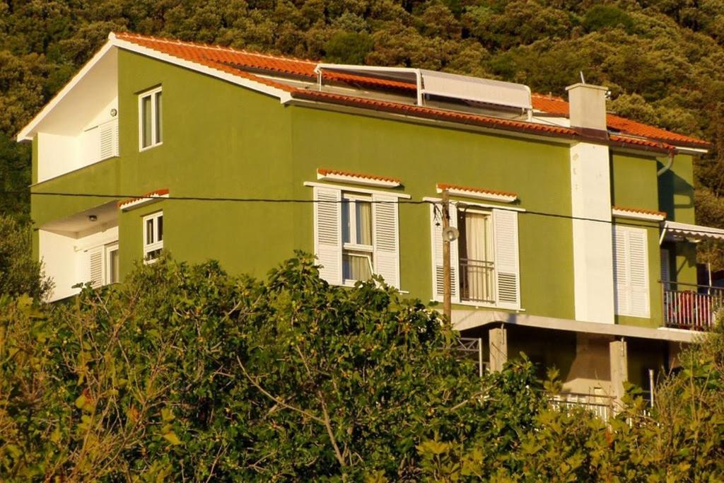 una casa verde e bianca con alberi di fronte di Apartments by the sea Supetarska Draga - Gornja, Rab - 21380 a Rab