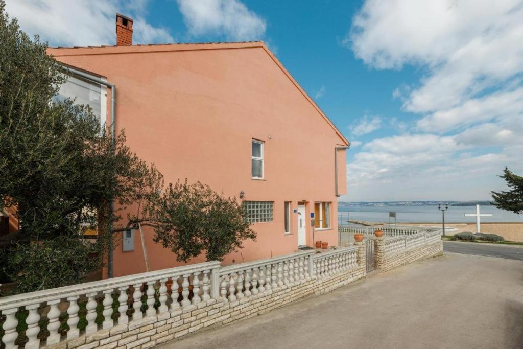a pink house with a fence next to the ocean at Apartments by the sea Tkon, Pasman - 21391 in Tkon