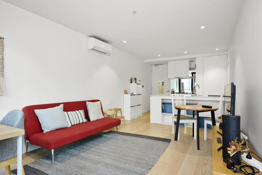 a living room with a red couch and a kitchen at Perfect Melbournian Escape - Close to Queen Vic Market in Melbourne