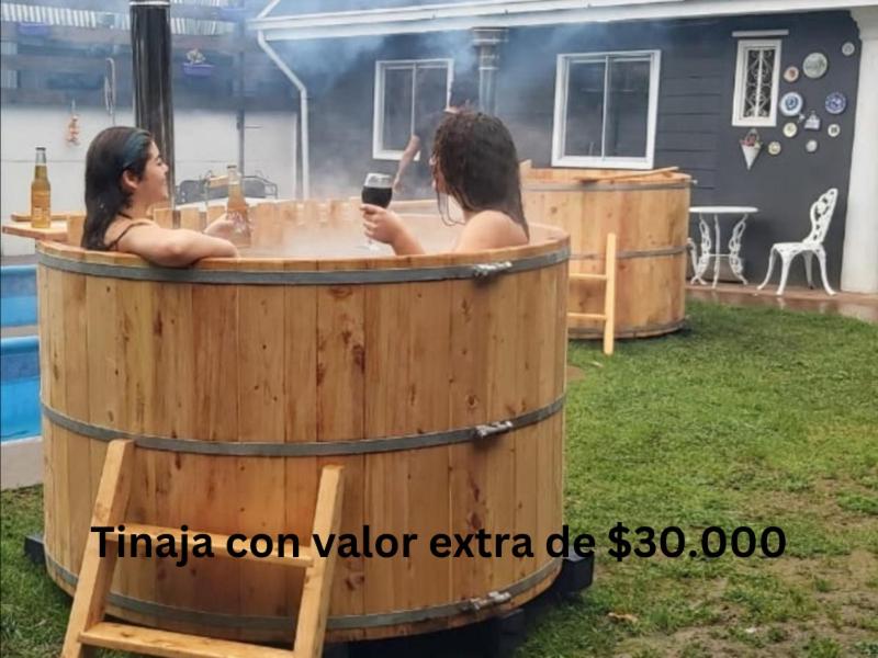 two women in a barrel hot tub in a yard at CABAÑA 2 TINAJA-PISCINA-QUINCHO in Valdivia