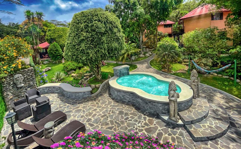 uma piscina num quintal com cadeiras e flores em Boquete Garden Inn em Boquete