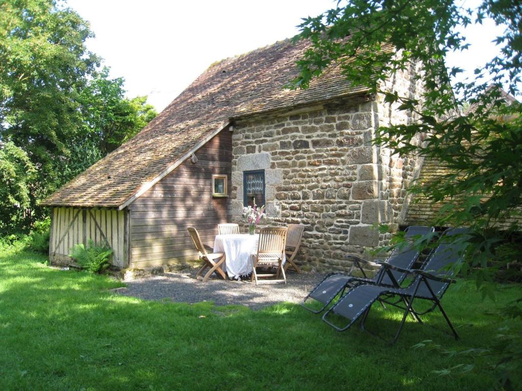 a table and chairs in front of a stone building at Cozy Holiday Home in Ceauc in Céaucé