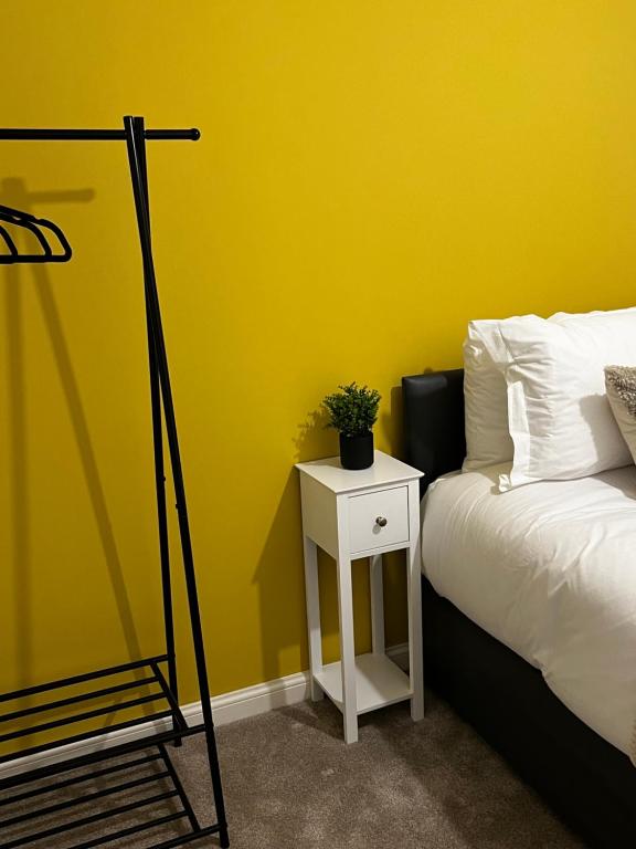 ein Schlafzimmer mit einer gelben Wand mit einem Bett und einem Nachttisch in der Unterkunft Comfy 2-bed home - Contractors and Leisure in West Bromwich