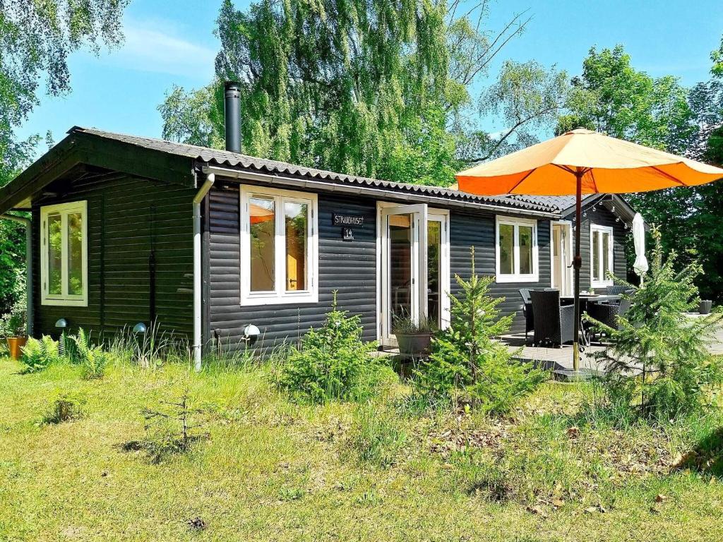 ein kleines Haus mit einem orangenen Regenschirm davor in der Unterkunft Holiday home Jægerspris XXXII in Jægerspris